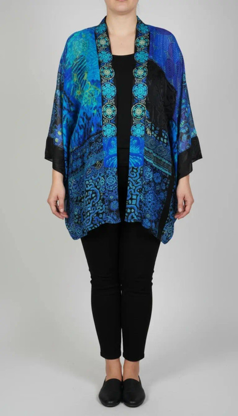 رویه شومیز زنانه فریسایز با ترکیب رنگ آبی‑سبز، آستین آزاد و فرم کِپ، روی تاپ مشکی، در پسزمینه روشن.»