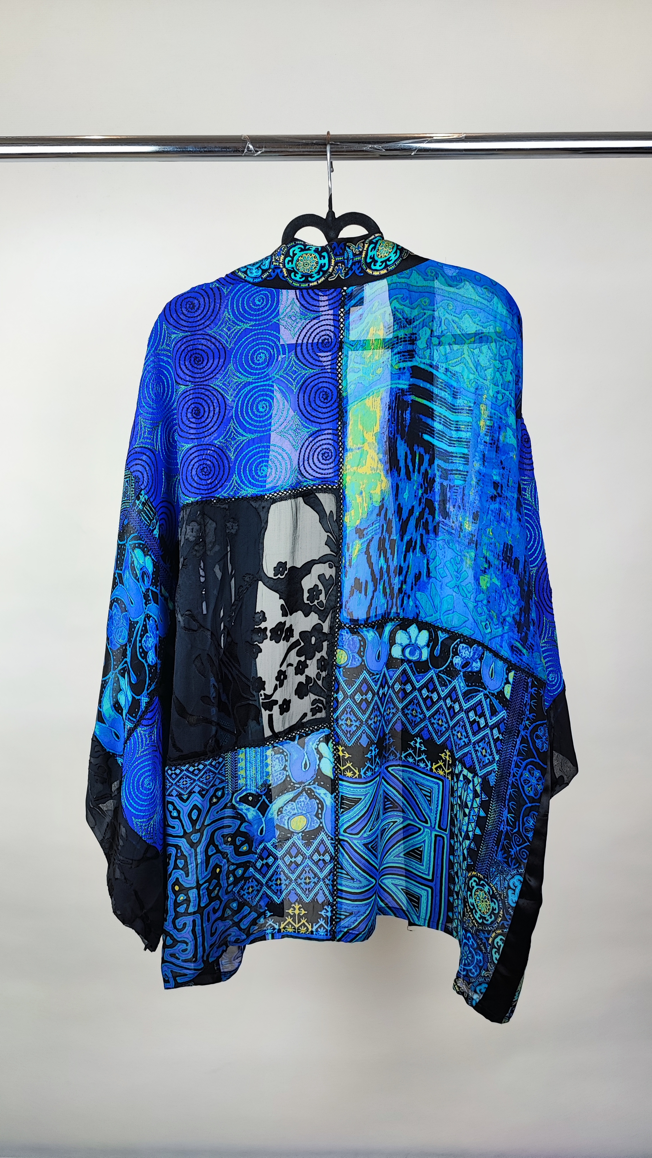 رویه شومیز زنانه فری‌سایز با ترکیب رنگ آبی‑سبز، آستین آزاد و فرم کِپ، روی تاپ مشکی، در پس‌زمینه روشن.»