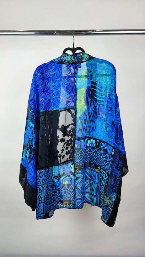 رویه شومیز زنانه فریسایز با ترکیب رنگ آبی‑سبز، آستین آزاد و فرم کِپ، روی تاپ مشکی، در پسزمینه روشن.»