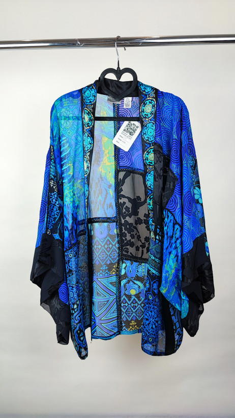 رویه شومیز زنانه فریسایز با ترکیب رنگ آبی‑سبز، آستین آزاد و فرم کِپ، روی تاپ مشکی، در پسزمینه روشن.»