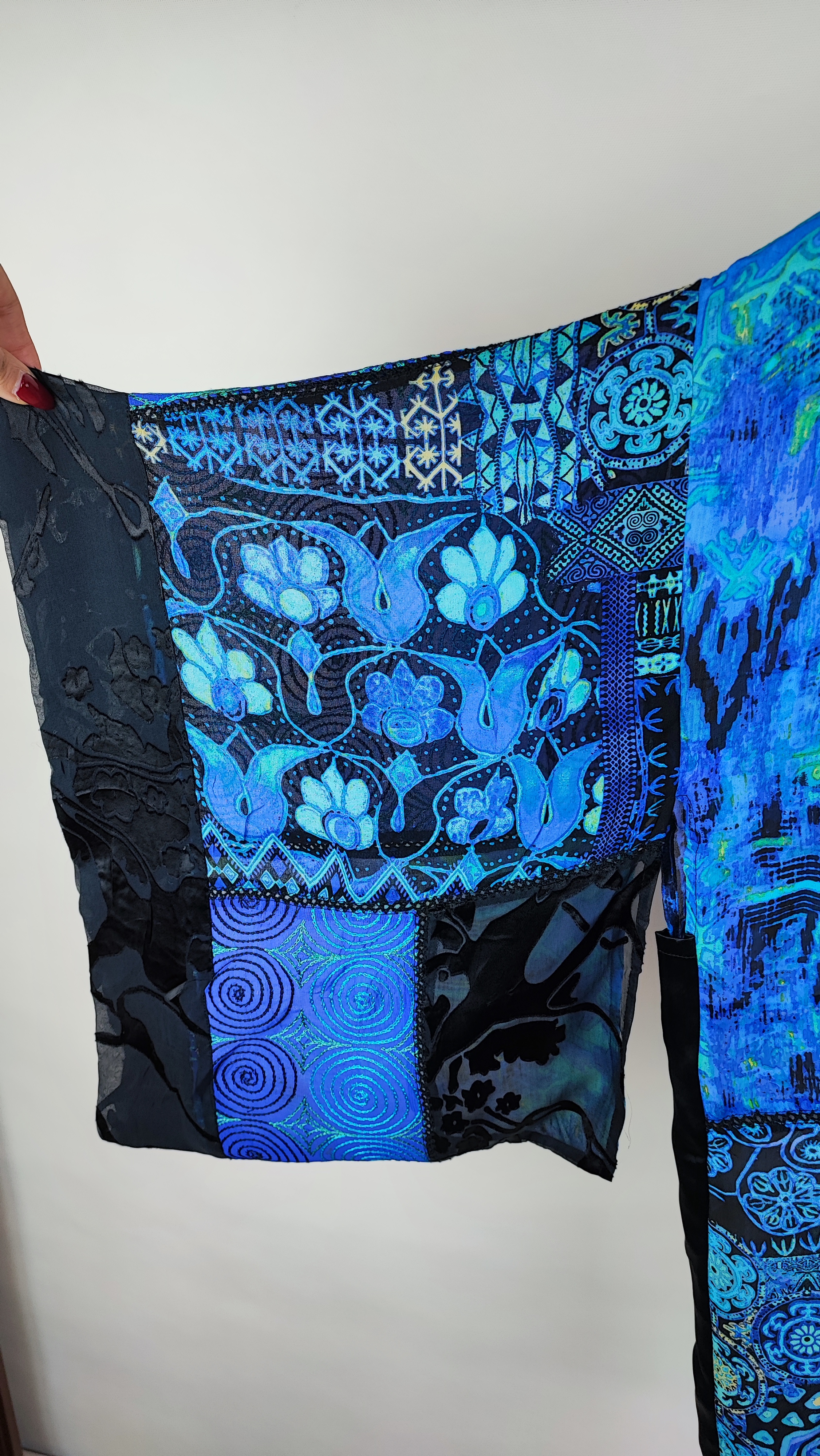 رویه شومیز زنانه فری‌سایز با ترکیب رنگ آبی‑سبز، آستین آزاد و فرم کِپ، روی تاپ مشکی، در پس‌زمینه روشن.»