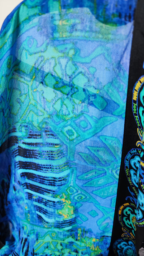 رویه شومیز زنانه فریسایز با ترکیب رنگ آبی‑سبز، آستین آزاد و فرم کِپ، روی تاپ مشکی، در پسزمینه روشن.»