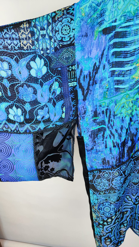 رویه شومیز زنانه فریسایز با ترکیب رنگ آبی‑سبز، آستین آزاد و فرم کِپ، روی تاپ مشکی، در پسزمینه روشن.»