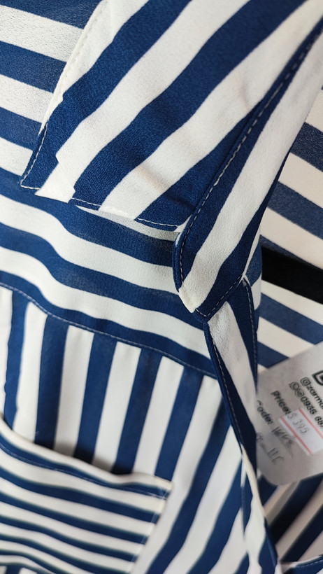 شومیز زنانه آبی راهراه سایز بزرگ با آستین بلند و مدل آزاد، روی تن مانکن با شلوار تیره، پسزمینه روشن.»