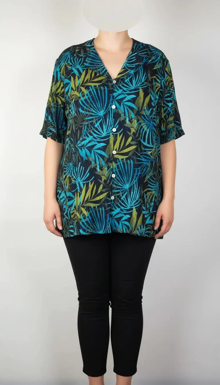 شومیز زنانه سایز بزرگ با زمینه سبزآبی و طرح گل‌های زرد و نارنجی، آستین کوتاه و فرم آزاد روی تن مانکن، پس‌زمینه روشن.»