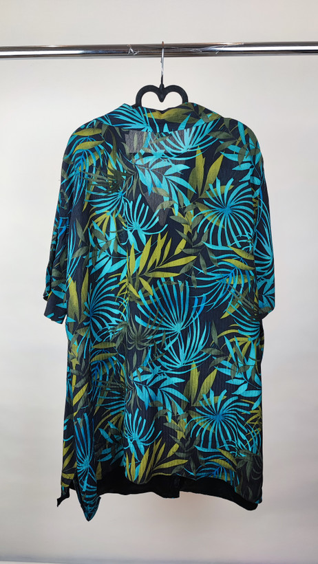 شومیز زنانه سایز بزرگ با زمینه سبزآبی و طرح گلهای زرد و نارنجی، آستین کوتاه و فرم آزاد روی تن مانکن، پسزمینه روشن.»