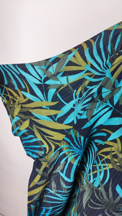 شومیز زنانه سایز بزرگ با زمینه سبزآبی و طرح گلهای زرد و نارنجی، آستین کوتاه و فرم آزاد روی تن مانکن، پسزمینه روشن.»