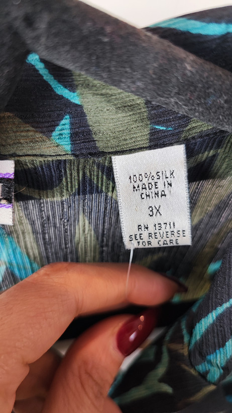 شومیز زنانه سایز بزرگ با زمینه سبزآبی و طرح گلهای زرد و نارنجی، آستین کوتاه و فرم آزاد روی تن مانکن، پسزمینه روشن.»