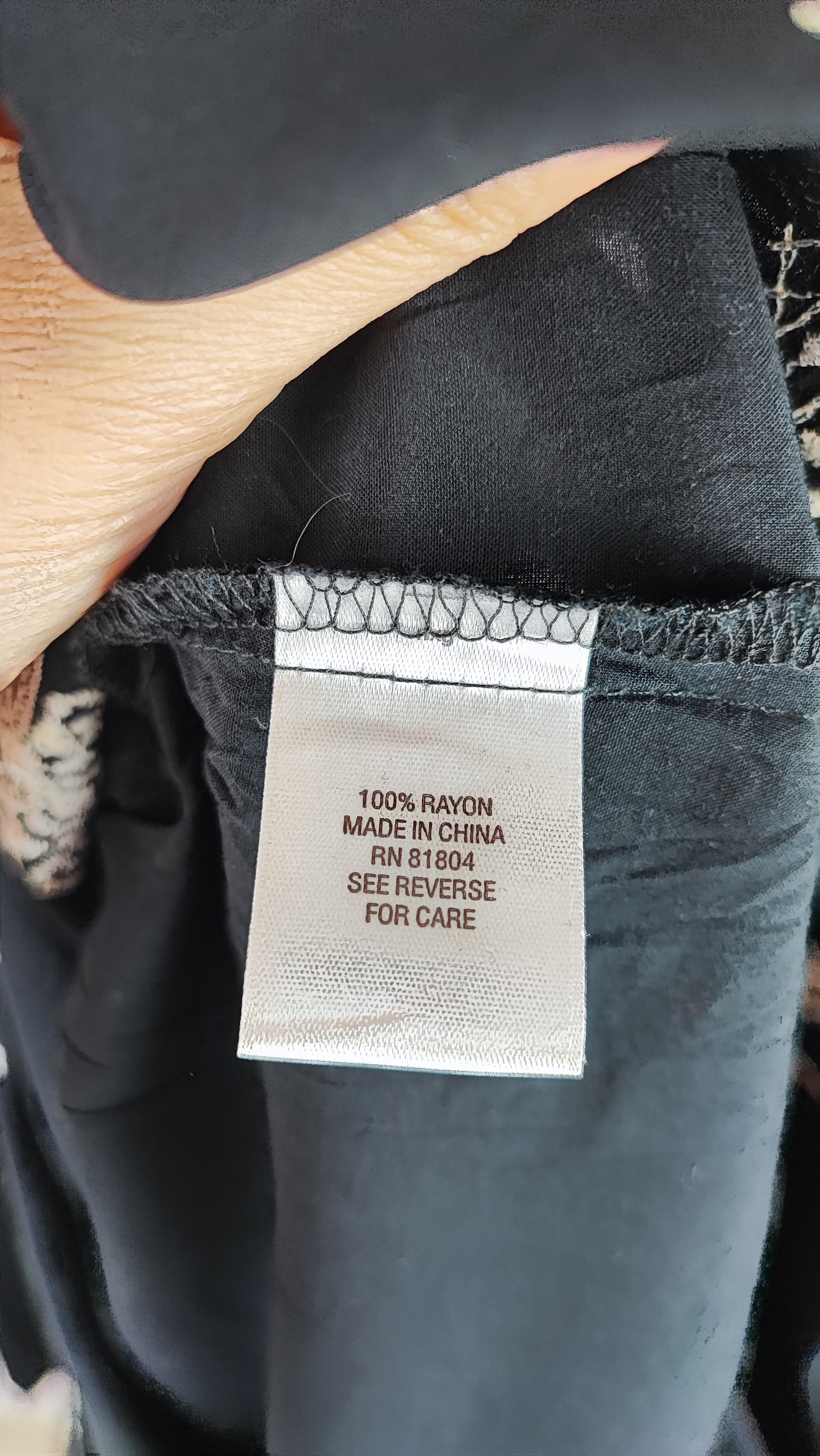 شومیز زنانه مشکی طرح‌دار با آستین بلند و فرم آزاد روی تن مانکن، پس‌زمینه روشن.»