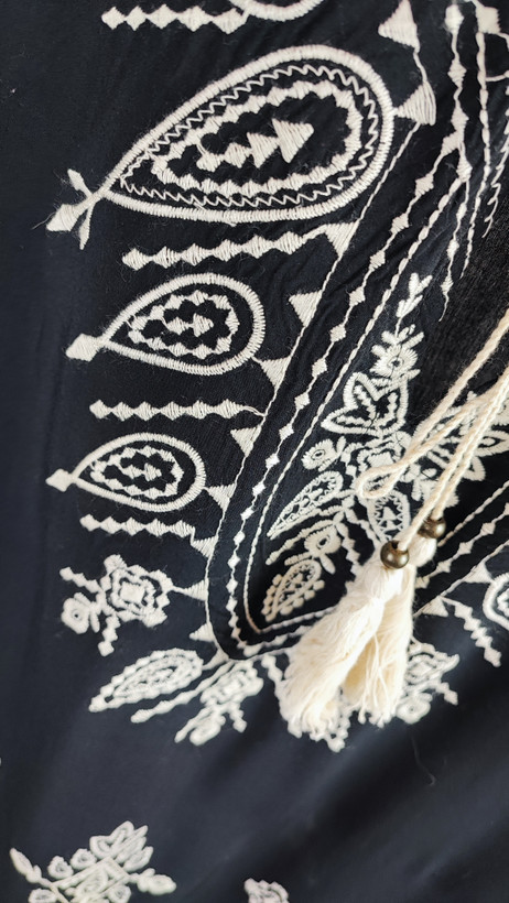 شومیز زنانه مشکی طرحدار با آستین بلند و فرم آزاد روی تن مانکن، پسزمینه روشن.»