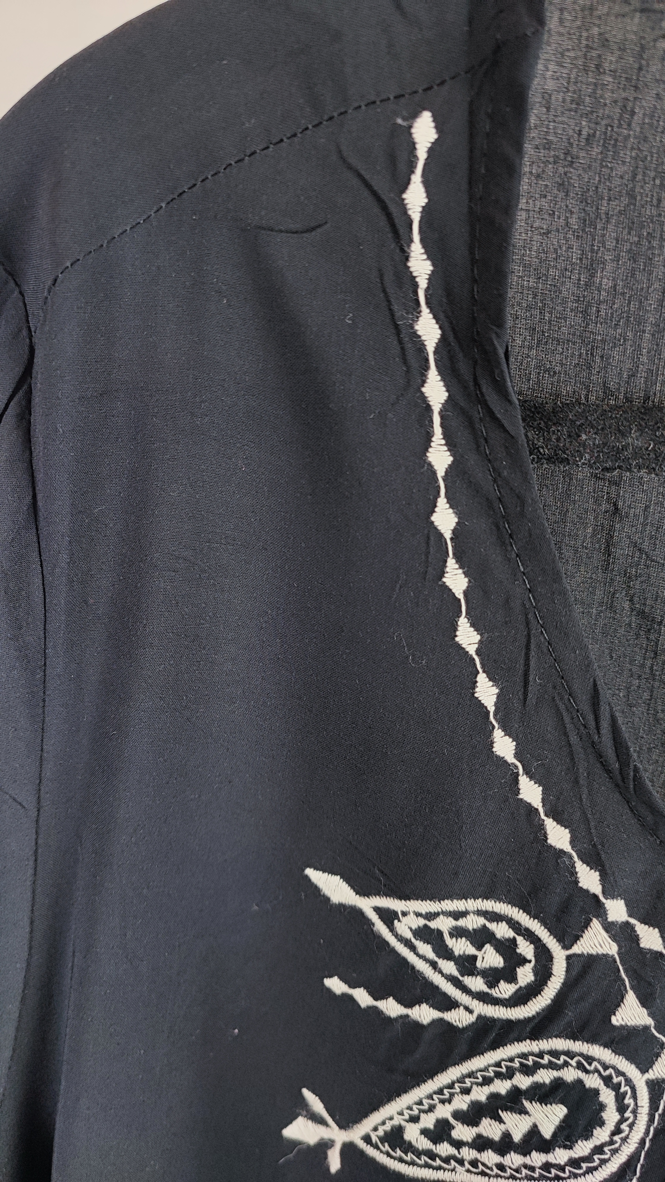 شومیز زنانه مشکی طرح‌دار با آستین بلند و فرم آزاد روی تن مانکن، پس‌زمینه روشن.»