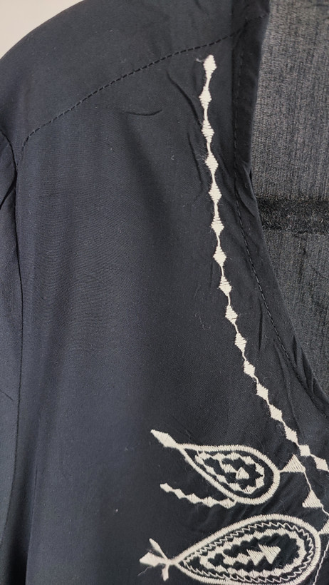 شومیز زنانه مشکی طرحدار با آستین بلند و فرم آزاد روی تن مانکن، پسزمینه روشن.»