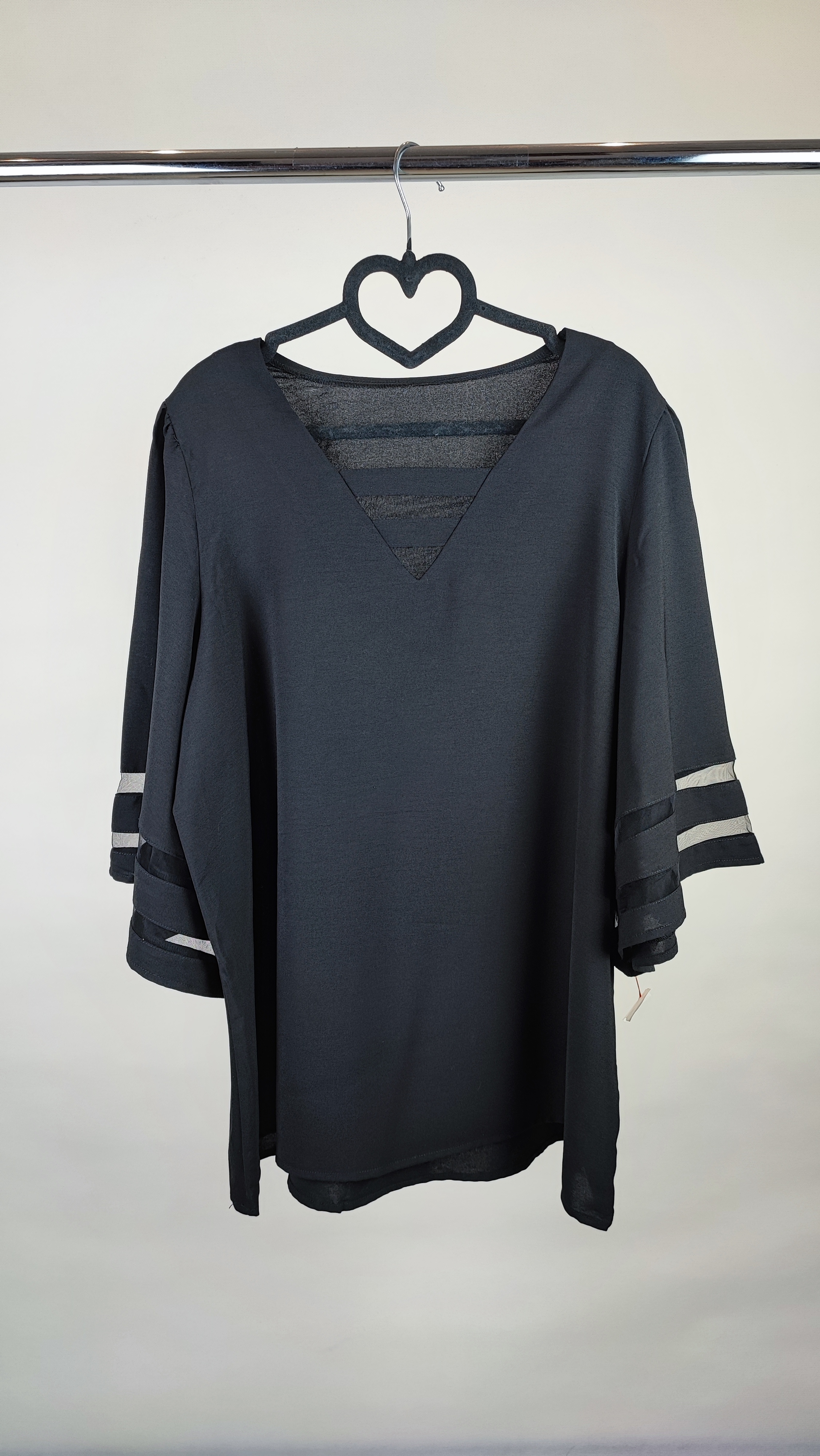 شومیز زنانه مشکی سایز بزرگ با آستین سه‌ربع و نوارهای تزیینی روی آستین، روی تن مانکن، پس‌زمینه روشن.