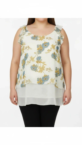 تاپ زنانه سایز بزرگ با پارچه سفید طرحدار ملایم سبز و آبی، بدون آستین، فرم آزاد و قد بلند روی تن مدل.