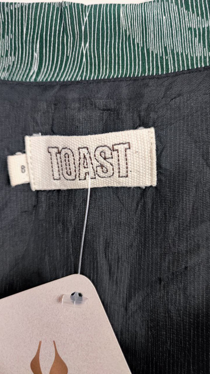 شومیز زنانه استوک برند TOAST طرحدار تیره با آستین کوتاه، مناسب سایز ۳۸–۴۰، فرم آزاد و راحت روی تن مدل.