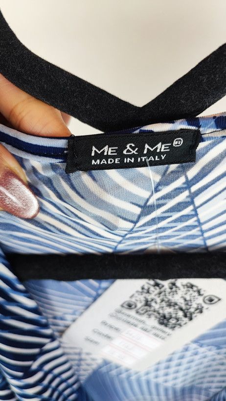 پیراهن زنانه استوک آبی طرحدار، آستین کوتاه، یقه ساده، قد بالای زانو، فرم مرتب و راحت، مناسب استایل روزمره، ایستاده روی مدل با پسزمینه روشن.