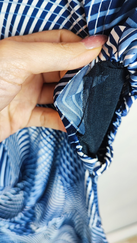 پیراهن زنانه استوک آبی طرحدار، آستین کوتاه، یقه ساده، قد بالای زانو، فرم مرتب و راحت، مناسب استایل روزمره، ایستاده روی مدل با پسزمینه روشن.