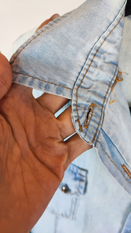 شومیز جین زنانه استوک آبی روشن، آستین بلند، یقه کلاسیک، فرم مرتب و کاربردی، مناسب استایل روزمره، ایستاده روی مدل با پسزمینه روشن.