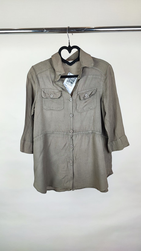 شومیز زنانه استوک رنگ خنثی، آستینسهربع، یقه ساده، فرم راحت و مرتب، مناسب استایل روزمره، ایستاده روی مدل با پسزمینه روشن.