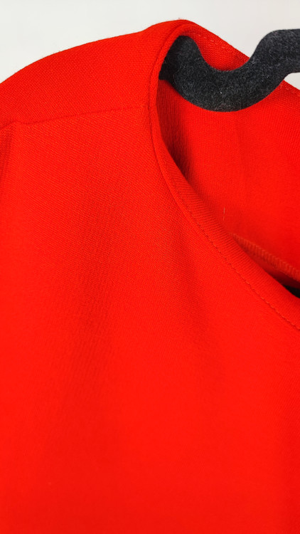 پیراهن زنانه استوک قرمز، آستین کوتاه با یقه باز، فرم ساده و جذب، قد میدی بلند، مناسب استایل رسمی و نیمهمجلس، ایستاده روی مدل با پسزمینه روشن.