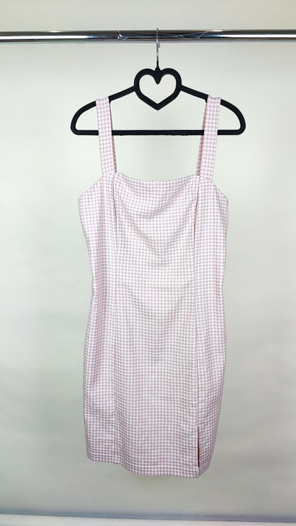 پیراهن زنانه استوک سفید/آفوایت، بدون آستین با یقه صاف و بند ظریف، فرم ساده و مینیمال، قد زیر زانو، تنخور مرتب و شیک، ایستاده روی مدل با پسزمینه روشن.