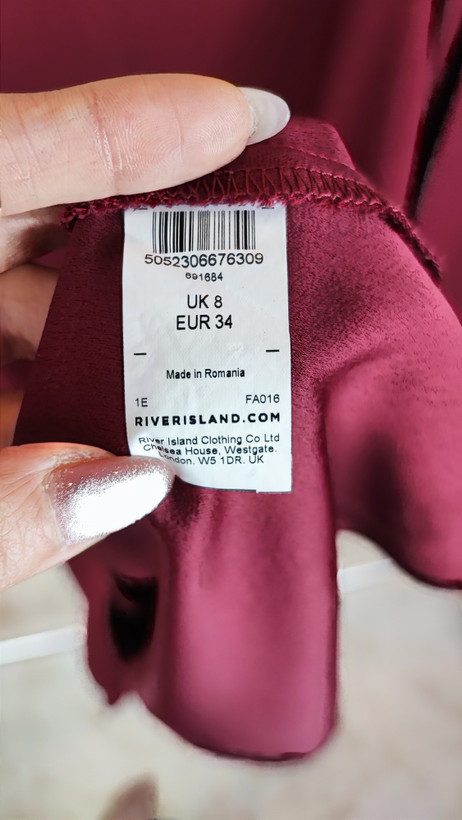 پیراهن زنانه استوک زرشکی، آستینبلند با یقه گرد باز، قد تا بالای زانو، فرم آزاد و ساده، مناسب استفاده روزمره و نیمهمجلس، ایستاده روی مدل با پسزمینه روشن.