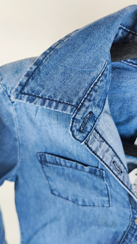 شومیز زنانه جین استوک آبی، آستین سهربع با یقه کلاسیک، قد متوسط و فرم ظریف، تنخوشومیز زنانه جین استوک آبی، آستین سهربع با یقه کلاسیک، قد متوسط و فرم ظریف، تنخور مرتب و جذب، ایستاده روی مدل با پسزمینه روشن.ر مرتب و جذب، ایستاده روی مدل با پسزمینه روشن.