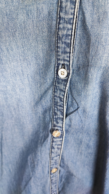 شومیز زنانه جین استوک آبی، آستین سهربع با یقه کلاسیک، قد متوسط و فرم ظریف، تنخور مرتب و جذب، ایستاده روی مدل با پسزمینه روشن.