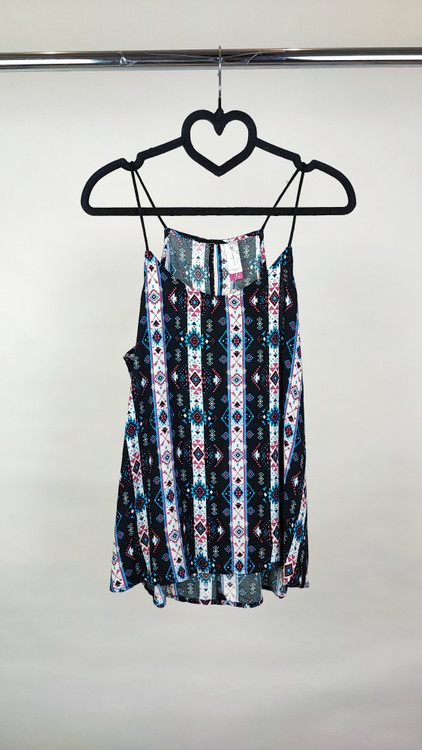 تاپ زنانه استوک طرحدار با ترکیب رنگ تیره، بندی و بدون آستین، فرم آزاد و قد متوسط، ایستاده روی مدل با پسزمینه روشن