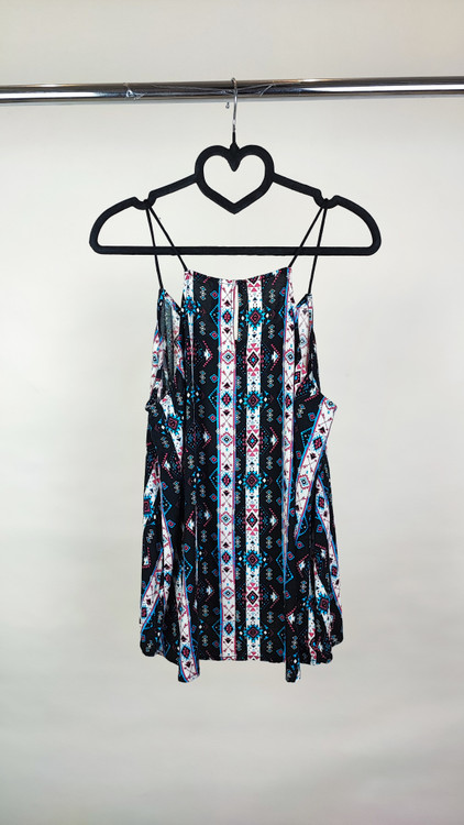 تاپ زنانه استوک طرحدار با ترکیب رنگ تیره، بندی و بدون آستین، فرم آزاد و قد متوسط، ایستاده روی مدل با پسزمینه روشن