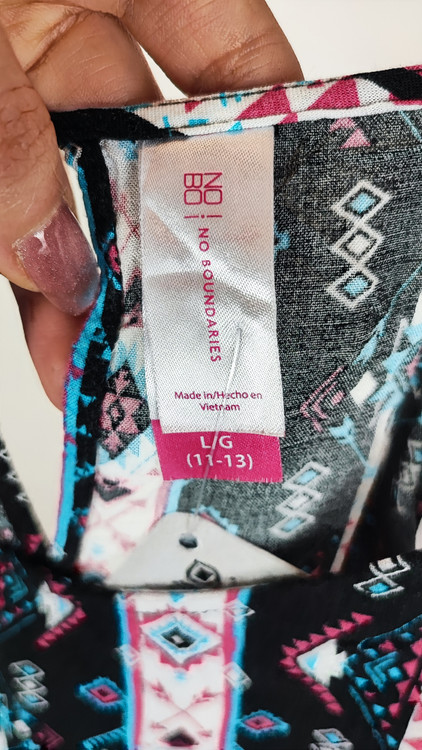 تاپ زنانه استوک طرحدار با ترکیب رنگ تیره، بندی و بدون آستین، فرم آزاد و قد متوسط، ایستاده روی مدل با پسزمینه روشن