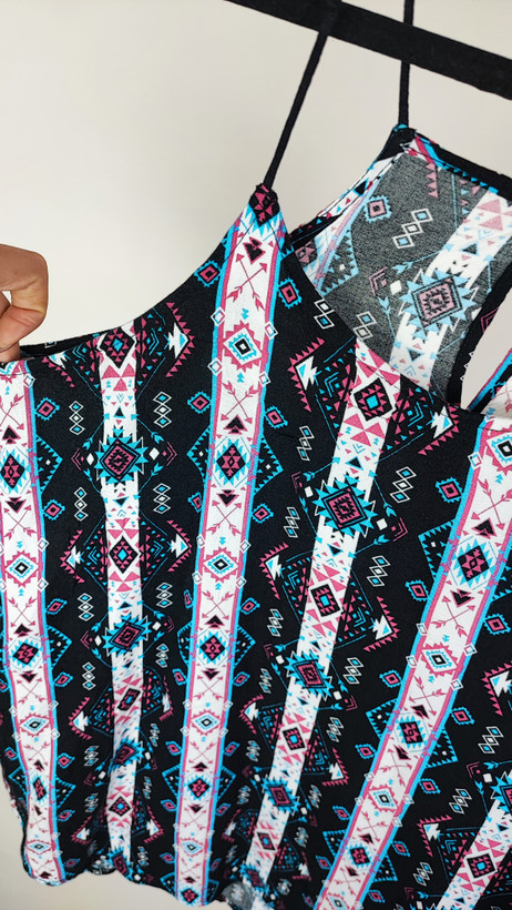 تاپ زنانه استوک طرحدار با ترکیب رنگ تیره، بندی و بدون آستین، فرم آزاد و قد متوسط، ایستاده روی مدل با پسزمینه روشن