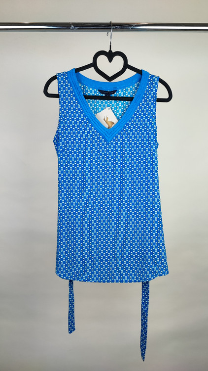 تاپ زنانه استوک وارداتی آبی با یقه هفت، بدون آستین، فرم ساده و جذب، مناسب استایل روزمره، روی تن مدل با پسزمینه روشن.