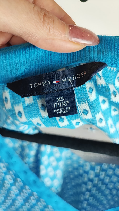 تاپ زنانه استوک وارداتی آبی با یقه هفت، بدون آستین، فرم ساده و جذب، مناسب استایل روزمره، روی تن مدل با پسزمینه روشن.