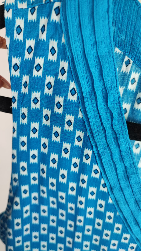 تاپ زنانه استوک وارداتی آبی با یقه هفت، بدون آستین، فرم ساده و جذب، مناسب استایل روزمره، روی تن مدل با پسزمینه روشن.