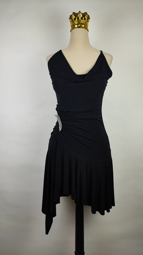 پیراهن زنانه وارداتی استوک مشکی بنددار، یقه هفت، فرم آزاد با پاییندوزی نامتقارن، قد حدود ۹۵ سانتیمتر، مناسب استایل مهمانی و شب، عکاسیشده روی تن با پسزمینه ساده روشن.