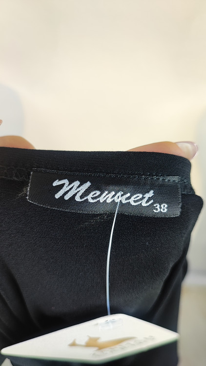 پیراهن زنانه وارداتی استوک مشکی بنددار، یقه هفت، فرم آزاد با پاییندوزی نامتقارن، قد حدود ۹۵ سانتیمتر، مناسب استایل مهمانی و شب، عکاسیشده روی تن با پسزمینه ساده روشن.