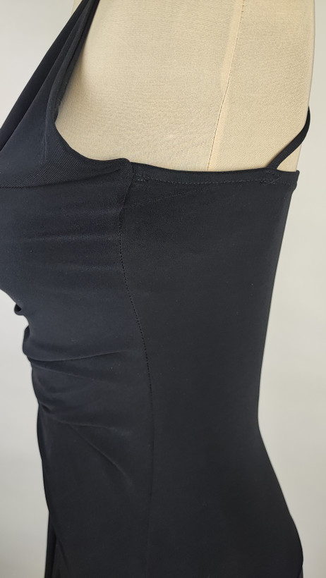 پیراهن زنانه وارداتی استوک مشکی بنددار، یقه هفت، فرم آزاد با پاییندوزی نامتقارن، قد حدود ۹۵ سانتیمتر، مناسب استایل مهمانی و شب، عکاسیشده روی تن با پسزمینه ساده روشن.