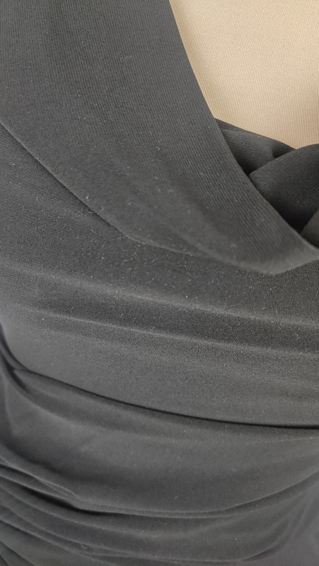 پیراهن زنانه وارداتی استوک مشکی بنددار، یقه هفت، فرم آزاد با پاییندوزی نامتقارن، قد حدود ۹۵ سانتیمتر، مناسب استایل مهمانی و شب، عکاسیشده روی تن با پسزمینه ساده روشن.