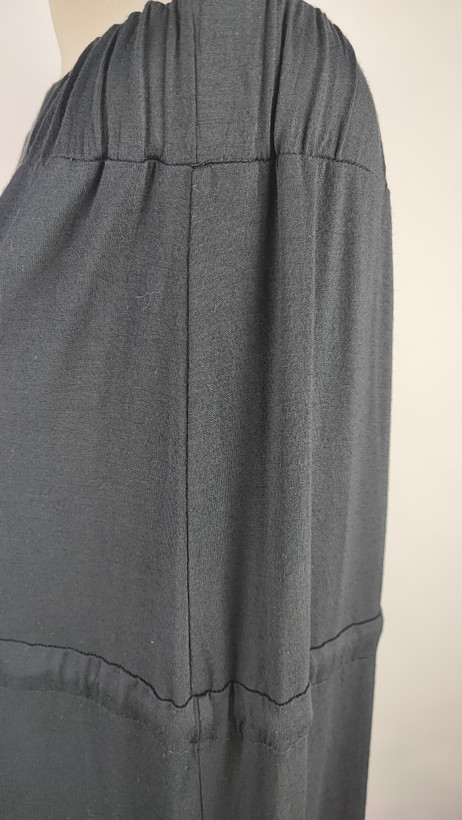 پیراهن زنانه وارداتی استوک مشکی بلند، دکلته بدون بند، فرم آزاد تا کف، عرض سینه ۵۵ و قد ۱۲۵ سانتیمتر، مناسب استایل رسمی و شب، عکاسیشده روی تن با بکگراند روشن ساده.