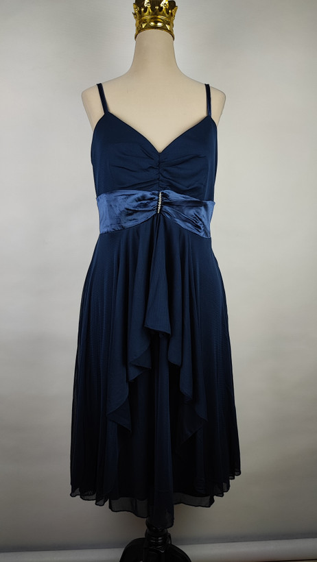 پیراهن زنانه استوک مشکی بنددار، یقه ضربدری، قد ۱۱۰ سانتیمتر، فرم آزاد و شیک، مناسب سایز ۴۲ تا ۴۴، مناسب مهمانی و استایل شب، عکاسیشده روی تن با پسزمینه روشن.