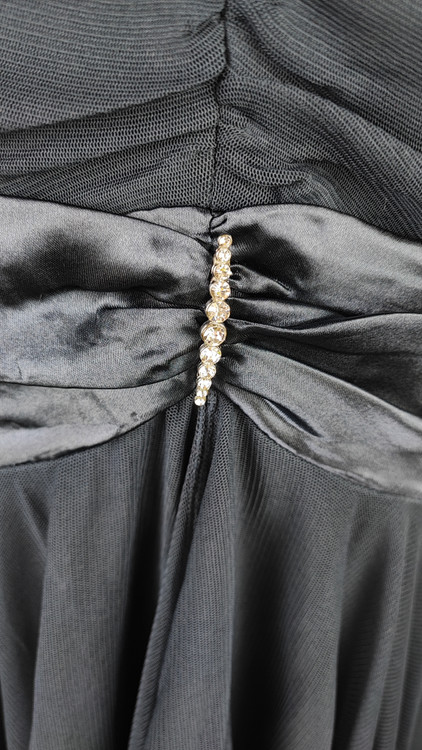 پیراهن زنانه استوک مشکی بنددار، یقه ضربدری، قد ۱۱۰ سانتیمتر، فرم آزاد و شیک، مناسب سایز ۴۲ تا ۴۴، مناسب مهمانی و استایل شب، عکاسیشده روی تن با پسزمینه روشن.