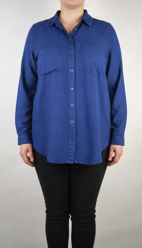 شومیز زنانه وارداتی استوک به رنگ آبی، مدل ساده و آزاد با یقه هفت و آستین بلند، مناسب سایز ۴۲–۴۴، عرض سینه ۵۵ و قد ۷۴ سانتیمتر، دارای ایراد، عکاسی روی تن با شلوار مشکی و پسزمینه روشن.