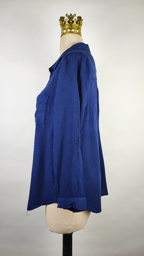 شومیز زنانه وارداتی استوک به رنگ آبی، مدل ساده و آزاد با یقه هفت و آستین بلند، مناسب سایز ۴۲–۴۴، عرض سینه ۵۵ و قد ۷۴ سانتیمتر، دارای ایراد، عکاسی روی تن با شلوار مشکی و پسزمینه روشن.