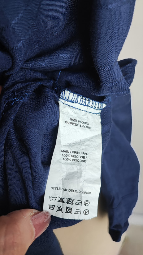 شومیز زنانه وارداتی استوک به رنگ آبی، مدل ساده و آزاد با یقه هفت و آستین بلند، مناسب سایز ۴۲–۴۴، عرض سینه ۵۵ و قد ۷۴ سانتیمتر، دارای ایراد، عکاسی روی تن با شلوار مشکی و پسزمینه روشن.