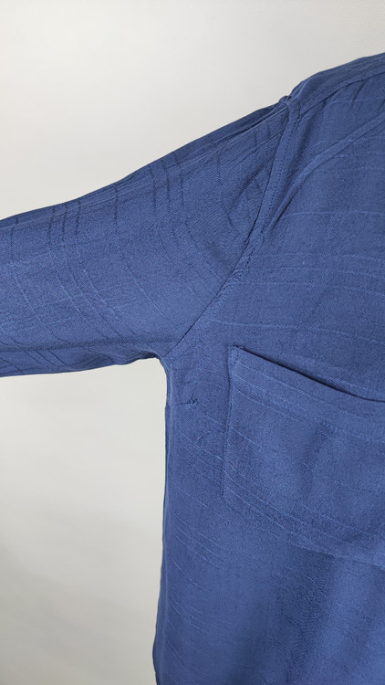 شومیز زنانه وارداتی استوک به رنگ آبی، مدل ساده و آزاد با یقه هفت و آستین بلند، مناسب سایز ۴۲–۴۴، عرض سینه ۵۵ و قد ۷۴ سانتیمتر، دارای ایراد، عکاسی روی تن با شلوار مشکی و پسزمینه روشن.