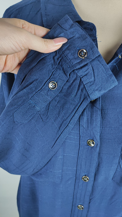 شومیز زنانه وارداتی استوک به رنگ آبی، مدل ساده و آزاد با یقه هفت و آستین بلند، مناسب سایز ۴۲–۴۴، عرض سینه ۵۵ و قد ۷۴ سانتیمتر، دارای ایراد، عکاسی روی تن با شلوار مشکی و پسزمینه روشن.