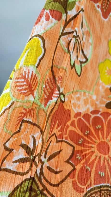 شومیز زنانه طرحدار نارنجی وارداتی با قواره آزاد کد ۱ * تصویر جزئیات: نمای نزدیک از زدگیهای جزئی در بافت پارچه شومیز استوک کد