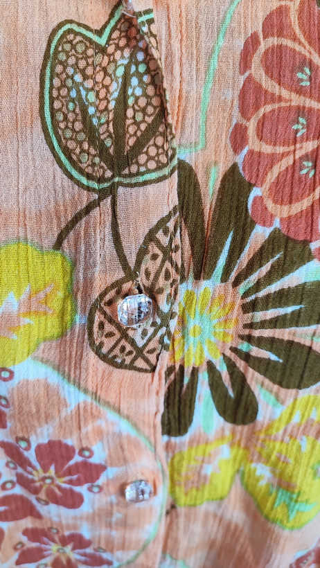 شومیز زنانه طرحدار نارنجی وارداتی با قواره آزاد کد ۱ * تصویر جزئیات: نمای نزدیک از زدگیهای جزئی در بافت پارچه شومیز استوک کد