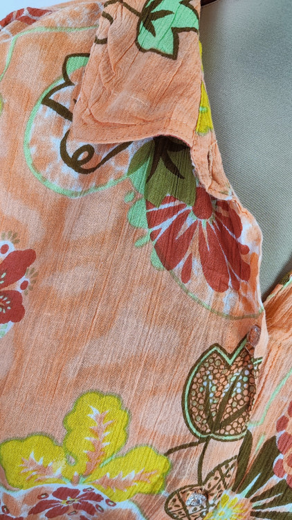 شومیز زنانه طرحدار نارنجی وارداتی با قواره آزاد کد ۱ * تصویر جزئیات: نمای نزدیک از زدگیهای جزئی در بافت پارچه شومیز استوک کد